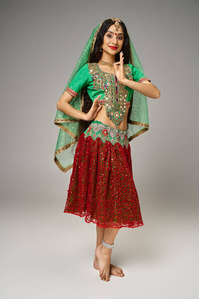 веселая красивая индийская женщина в традиционном чоли и юбке жестикулирует и смотрит в камеру