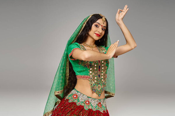 joyful young indian woman in traditional clothes posing on floor and gesturing, looking at camera