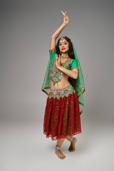 vertical shot of indian pretty woman with long hair and bindi dancing lively and looking at camera