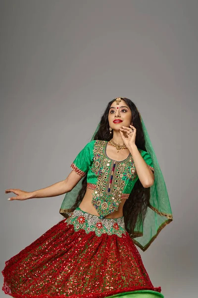 stock image attractive jolly indian woman with bindi dot posing while dancing actively on gray background