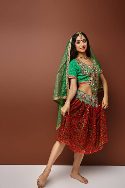 вертикальный снимок привлекательной индийской женщины в национальном костюме с аксессуарами, улыбающимися в камеру