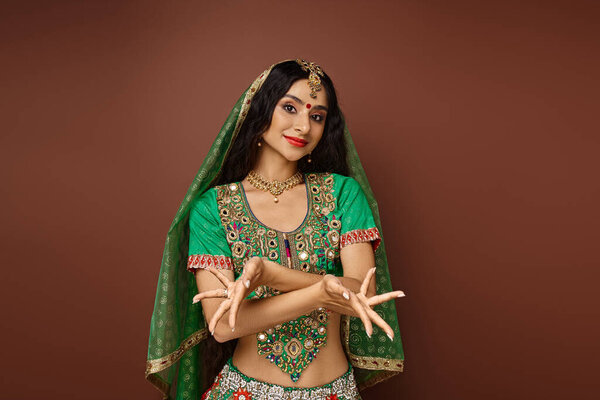 радостная длинноволосая индианка в традиционном костюме с аксессуарами, жестикулирующими руками