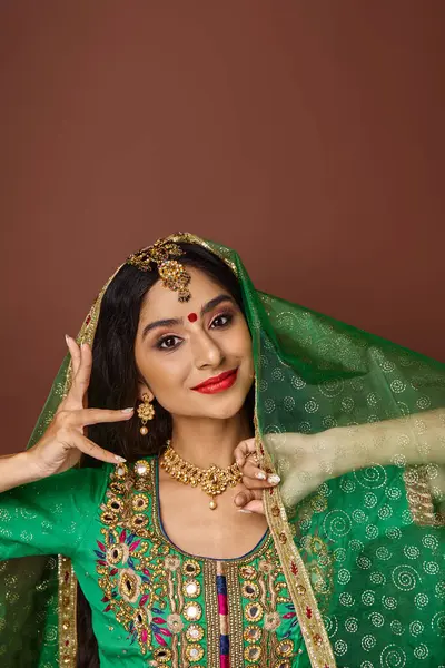 Güzel Hintli bir kadının dans ederken ve kameraya bakarken el kol hareketi yaptığı dikey çekim.