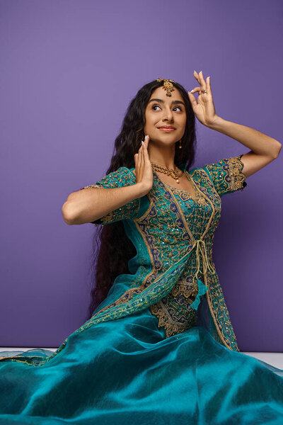 vertical shot of beautiful jolly indian woman in national costume gesturing and sitting on floor