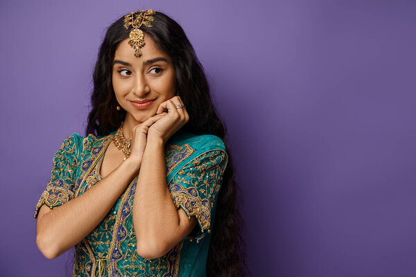 young indian woman in national costume with accessories posing on purple backdrop and looking away