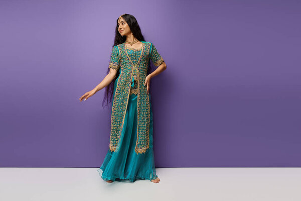 красивая молодая индийская женщина с длинными волосами в голубом сари с аксессуарами на фиолетовом фоне