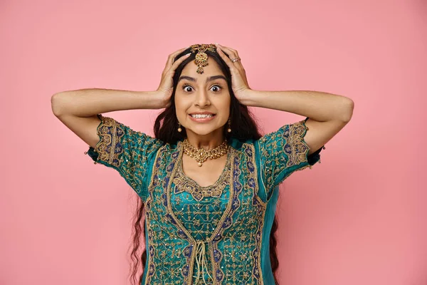 stock image amazed young indian woman in traditional clothes posing with hands on head and looking at camera