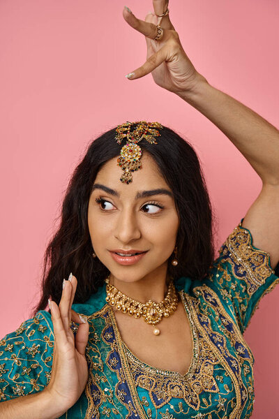 attractive jolly young indian woman in national costume gesturing while dancing and looking away