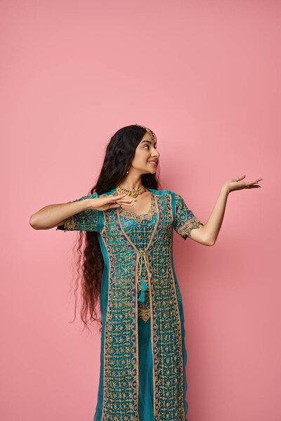 vertical sot of attractive young indian woman in traditional attire gesturing while dancing lively