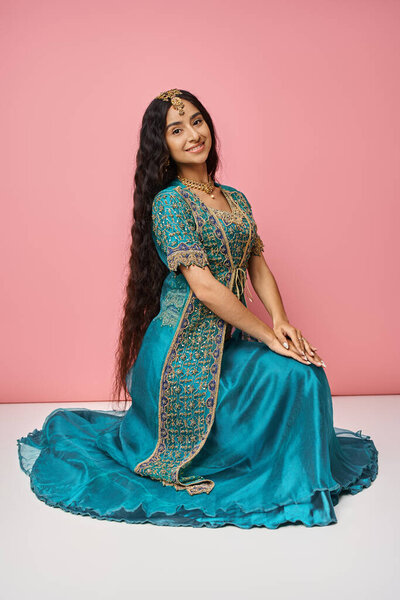 vertical shot of good looking young indian woman in national costume posing on pink backdrop