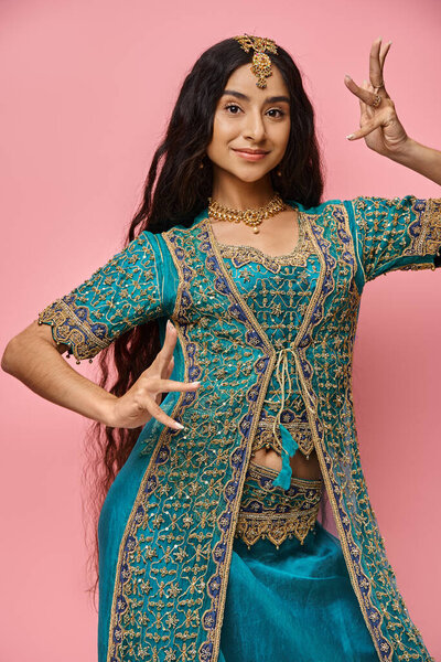 vertical shot of beautiful indian woman in national costume with accessories on pink backdrop