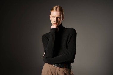 İyi görünümlü, ikili olmayan, kameraya bakan, çene altı yumruk, moda kavramı.