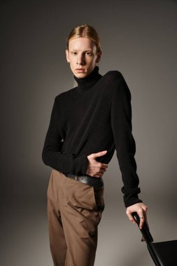 Güzel görünümlü, at kuyruklu, siyah sandalyede poz veren, ikili olmayan genç model.