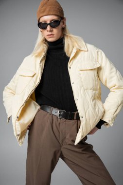 Güneş gözlüklü ve bere şapkalı modaya ve kameraya bakan modaya uygun olmayan trend şahsın dikey çekimi