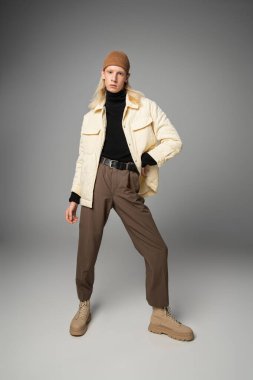Tek kolu kalçasında kameraya bakan, kışlık ceketli, ikiz olmayan genç ve yakışıklı bir adam.