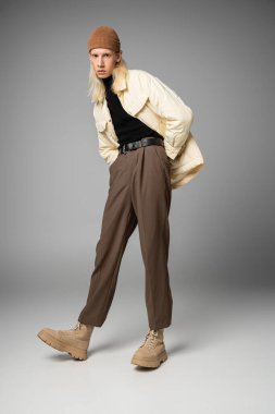 Moda kış giysileri içinde, elleri ceplerinde genç ve çekici, ikilik olmayan birinin dikey çekimi.