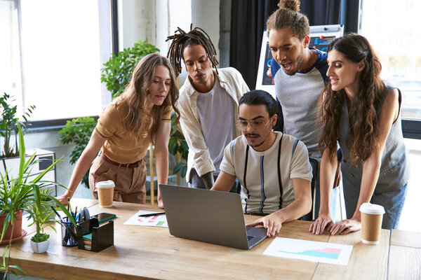 творческий коллектив возглавляет работу за ноутбуком рядом амбициозных и вдохновленных мультиэтнических коллег в офисе
