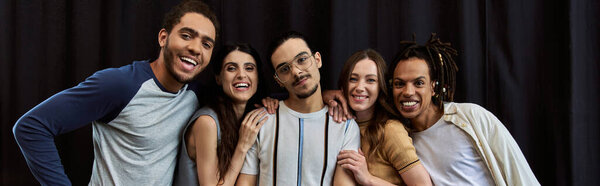 кадр счастливой многонациональной команды, смотрящей на камеру рядом с черным драпировщиком в офисе, держащей в руках плакат