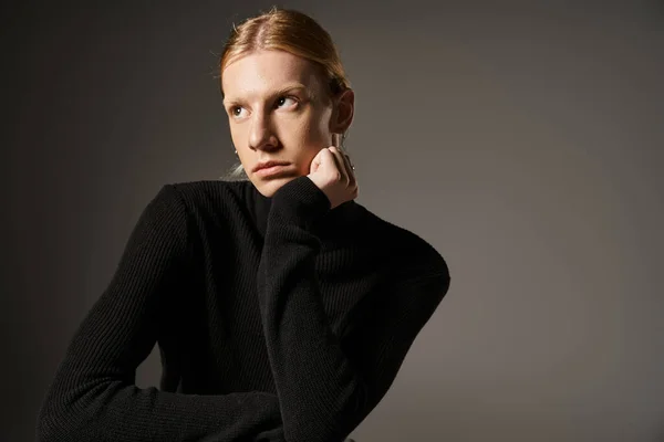 good looking young non binary person in black turtleneck posing and looking away, fashion concept