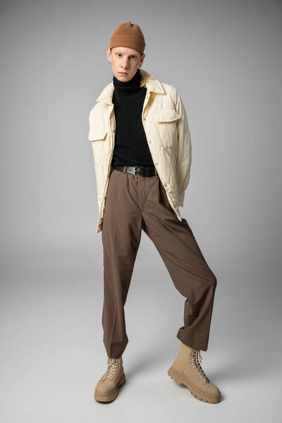 vertical shot of non binary stylish person in winter attire posing and looking at camera, fashion