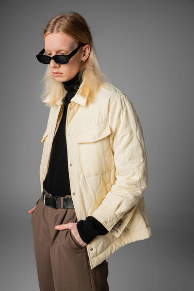 вертикальный снимок длинноволосых небинарных моделей в зимнем наряде с солнцезащитными очками, смотрящих вниз, мода