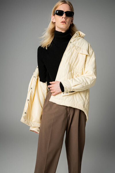 вертикальный снимок хорошо выглядящего андрогинного человека в стильной одежде, смотрящего на камеру, моду