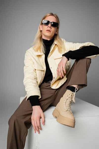 vertical shot of stylish androgynous person in winter jacket and trendy sunglasses, fashion concept