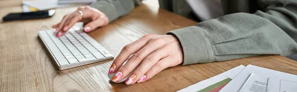 cropped view of hands of androgynous person working at table in office, business concept, banner