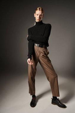 Siyah yakalı balıkçı yakalı, kızıl saçlı çift cinsiyetli bir model kameraya bakıyor.