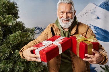 good looking Santa with white beard in warm jacket holding presents and smiling cheerfully, winter clipart