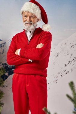 Noel Baba kostümü giymiş neşeli beyaz sakallı adam kameraya gülümsüyor, kış konsepti.