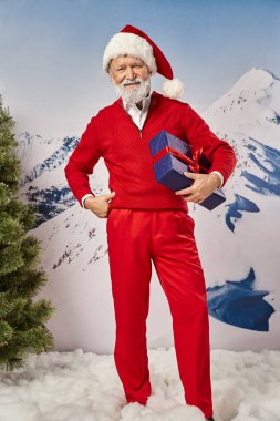 Neşeli Noel Baba 'nın bir eli kalçasında, karlı dağ zemininde, kış konsepti