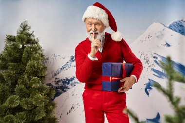 mysterious bearded Santa holding present and showing silence gesture at camera, winter concept clipart