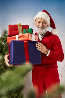 Kırmızı Noel Baba kostümlü neşeli adam elinde hediyelerle kameraya gülümsüyor, kış konsepti.