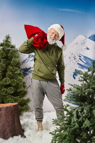 stock image athletic Santa in warm christmassy hat and mittens holding red huge present bag, winter concept