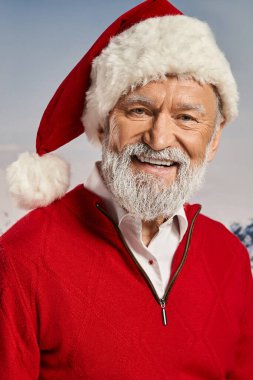 Kırmızı kıyafetli neşeli Noel Baba 'nın dikey görüntüsü kameraya karlı arka planla gülümsüyor, kış konsepti.