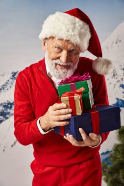 Noel Baba gibi giyinmiş neşeli sakallı adam elinde hediyelerle Noel şapkası, kış konsepti