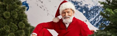 cheerful man dressed as Santa Claus in christmassy hat with snowy backdrop, winter concept, banner clipart