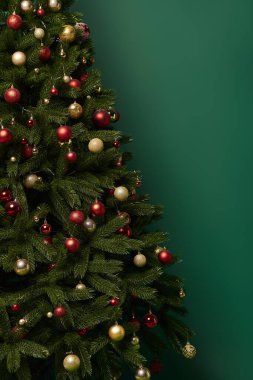 Koyu yeşil arka planda güzel mücevherleri olan süslü Noel ağacı, kış konsepti