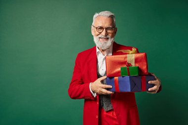 Gözlüklü neşeli Noel Baba hediyelerle poz veriyor ve kameraya gülümsüyor, Noel konsepti.