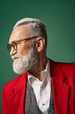 portrait of handsome classy Santa Claus posing in profile on dark green backdrop, winter concept clipart