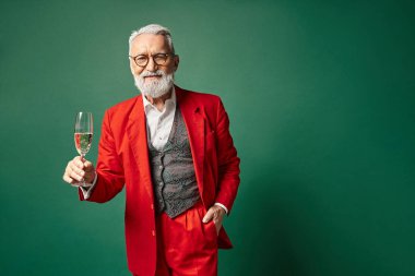 Güzel görünümlü beyaz sakallı Noel Baba şampanya ile poz veriyor ve bir eli cebinde, kış konsepti