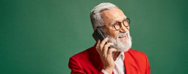 Şık kırmızı elbiseli neşeli Noel Baba telefonla konuşuyor ve başka yere bakıyor, kış konsepti, afiş