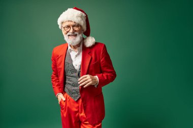Kırmızı Noel şapkalı ve gözlüklü yakışıklı zarif Noel Baba kameraya bakıyor, kış konsepti.