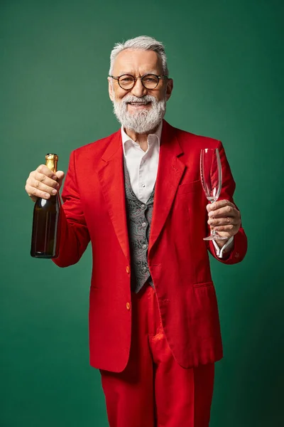 stock image happy Santa with glasses and beard in red suit posing with champagne bottle, winter concept
