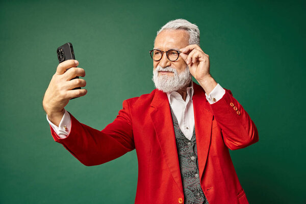 стильный красивый мужчина одетый как элегантный Санта делает серьезные селфи по телефону, зимняя концепция