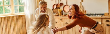 Heyecanlı ebeveynler evdeki modern mutfakta mutlu kızlarıyla oynuyorlar, aile etkileşimi, afiş