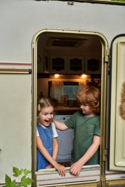 redhead boy looking at excited sister with open mouth in trailer home, siblings family relationship clipart