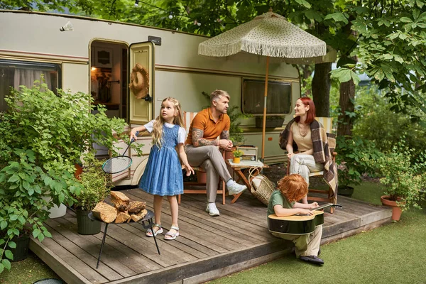 stock image children playing badminton and acoustic guitar near parents sitting next to modern trailer home