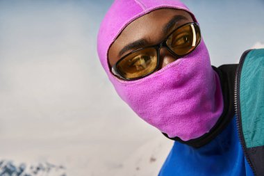 Pembe parlak kar maskeli genç Afro-Amerikan adamın portresi, kış konsepti.